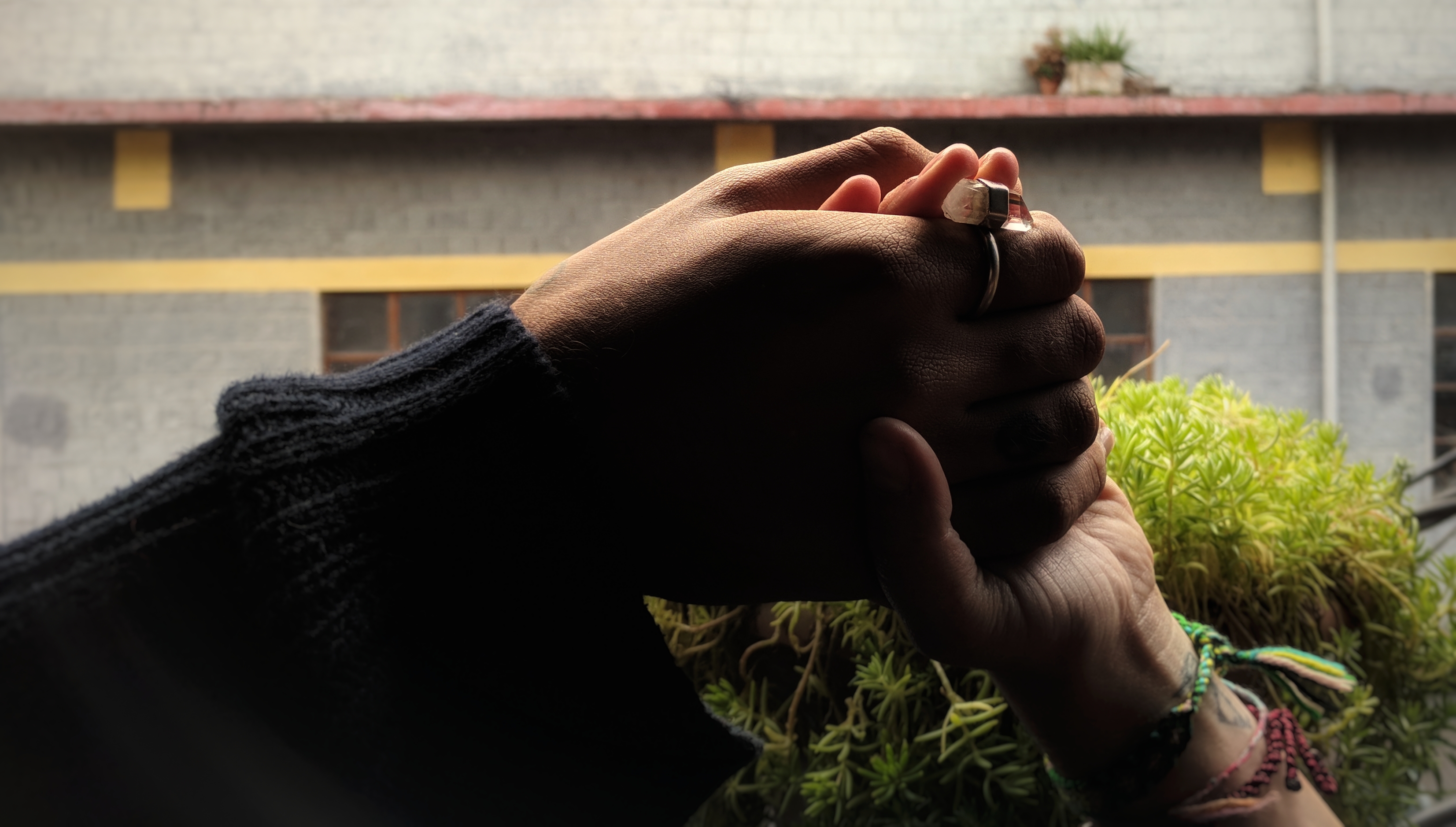 A photo of two hands gently clasped, each arm extending from either side to the center.